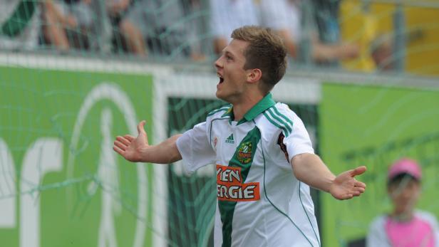 Ein Fußballspieler jubelt mit ausgestreckten Armen auf dem Spielfeld.