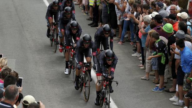Eine Gruppe Radrennfahrer des Teams Bora fährt ein Rennen, während Zuschauer am Straßenrand stehen und applaudieren.
