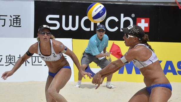 Zwei Beachvolleyballspielerinnen baggern den Ball über das Netz.