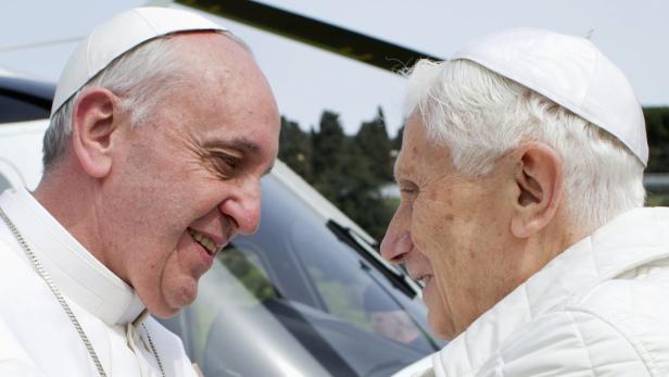 Papst Franziskus und Papst Benedikt XVI. stehen einander gegenüber.