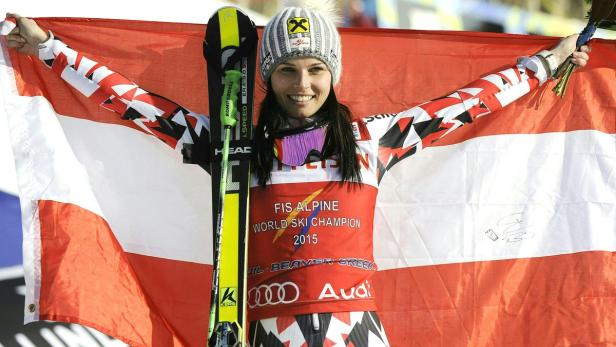 Eine strahlende Skirennläuferin mit der österreichischen Flagge und ihren Skiern.