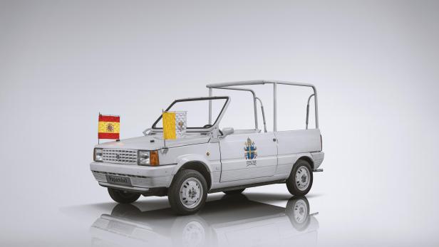 Ein weißer Papamobil mit spanischer und vatikanischer Flagge.