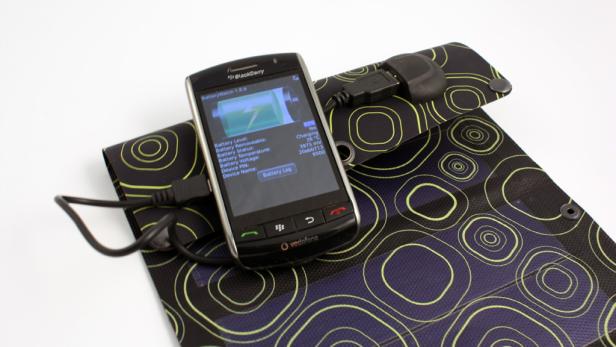 Ein Blackberry-Smartphone wird über ein Solarpanel mit einem USB-Kabel aufgeladen.