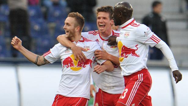 Drei Fußballspieler von Red Bull umarmen sich und jubeln.