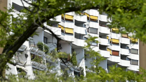 Ein Wohnhaus mit vielen Balkonen, teilweise mit gelben Markisen und Pflanzen geschmückt.