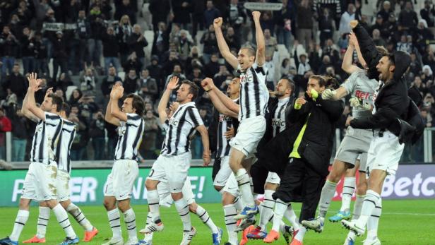 Eine Gruppe von Juventus-Spielern jubelt auf dem Spielfeld vor einer Zuschauermenge.