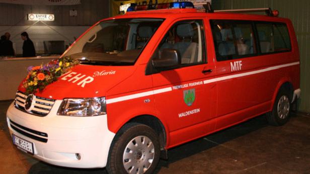 Ein rotes Feuerwehrfahrzeug mit Blumenschmuck auf der Motorhaube.