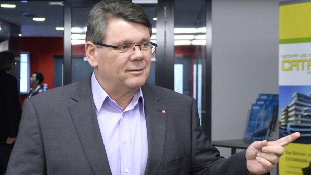 Ein Mann mit Brille und Anzug gestikuliert mit dem Finger.