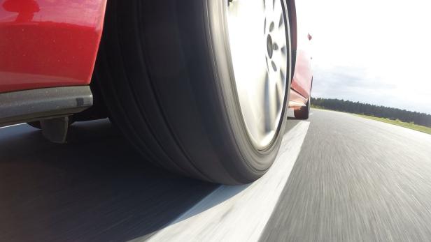 Ein rotes Auto fährt auf einer asphaltierten Straße.