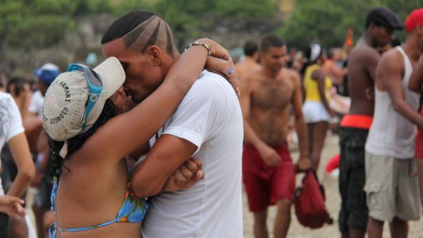 Ein Paar umarmt sich am Strand vor einer Menschenmenge.