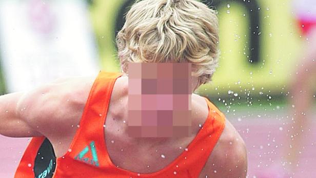 Ein Athlet mit blonden Haaren und einem orangefarbenen Trikot wird mit Wasser bespritzt.