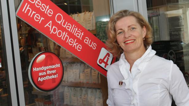 Eine freundliche Apothekerin steht vor ihrer Apotheke mit dem Slogan „Beste Qualität aus Ihrer Apotheke“.