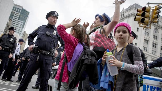 Eine Gruppe von Menschen, darunter Kinder, wird von New Yorker Polizisten umringt.