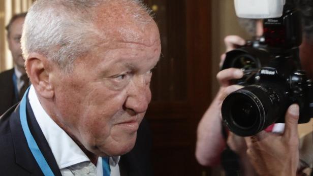 Ein Mann mit einer blauen Schärpe wird von einem Fotografen fotografiert.