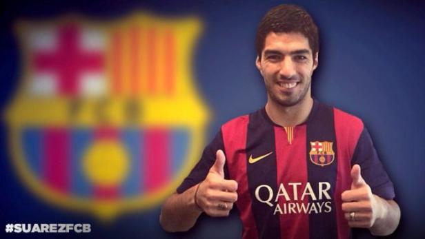 Luis Suárez im Trikot des FC Barcelona mit erhobenem Daumen vor dem Vereinswappen.