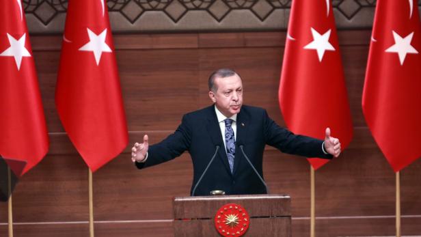 Recep Tayyip Erdoğan hält eine Rede vor türkischen Flaggen.
