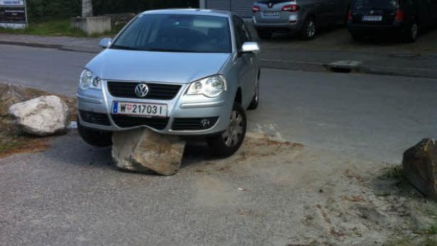 Ein silberner VW Polo steht auf einem großen Stein.