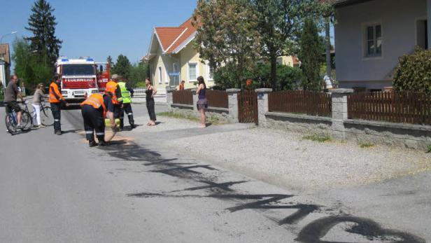 Die Feuerwehr reinigt die Straße von Öl nach einem Unfall.