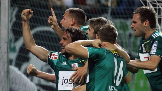 Eine Gruppe von Fußballspielern in grünen Trikots feiert ein Tor.