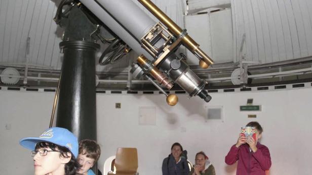 Besucher betrachten ein großes Teleskop in einer Sternwarte.
