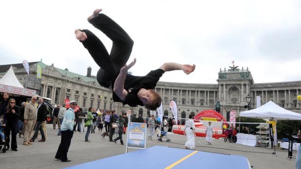 Ein Mann macht einen Salto vor der Hofburg in Wien.