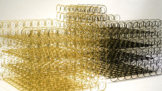 Eine Nahaufnahme von goldenen und schwarzen Sprungfedern, die ein abstraktes Muster bilden.