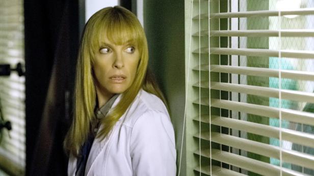 Eine Frau im weißen Kittel blickt besorgt zur Seite.