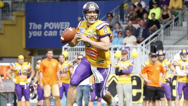 Ein American-Football-Spieler im gelb-violetten Trikot wirft den Ball.