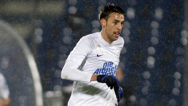 Ein Fußballspieler im weißen Trikot während eines Spiels im Regen.