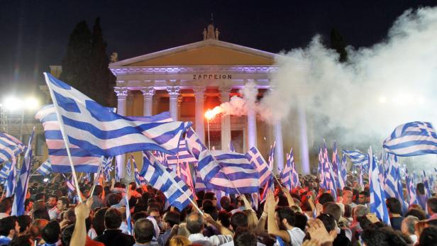 Eine Menschenmenge schwenkt griechische Flaggen vor dem Zappeion in Athen.