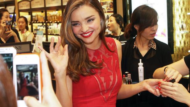 Miranda Kerr lächelt und winkt, während sie sich die Nägel lackieren lässt.
