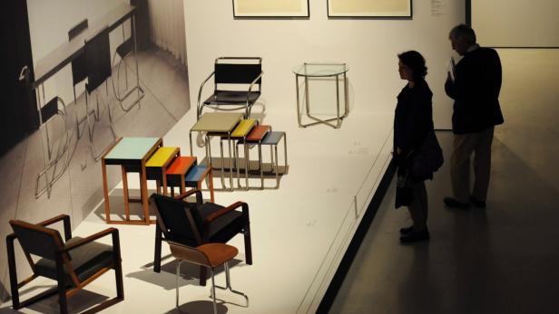 Besucher betrachten eine Ausstellung von Bauhaus-Möbeln.