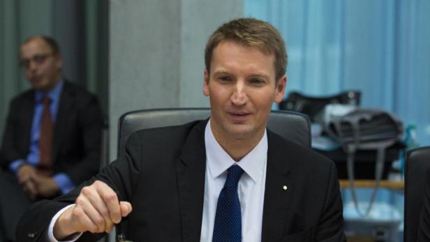 Ein Mann im Anzug sitzt an einem Tisch.