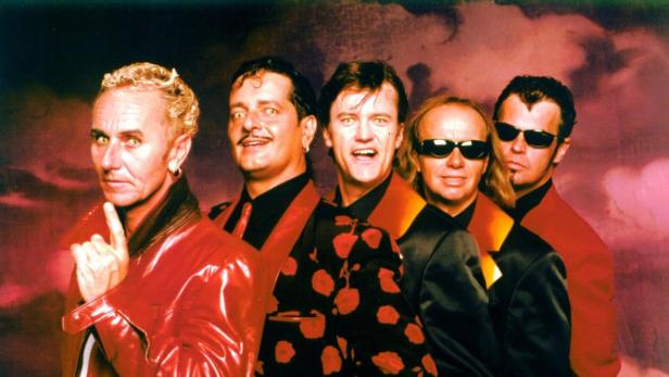 Die britische Rockband The Stranglers posiert mit gelben Augen vor einem roten Hintergrund.