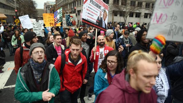 Eine Menschenmenge demonstriert mit Schildern gegen Donald Trump.