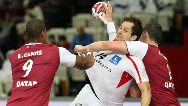 Ein Handballspieler wird von zwei Verteidigern der Mannschaft Katar bedrängt.