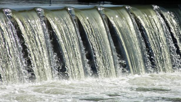 Wasser fließt über ein Wehr.