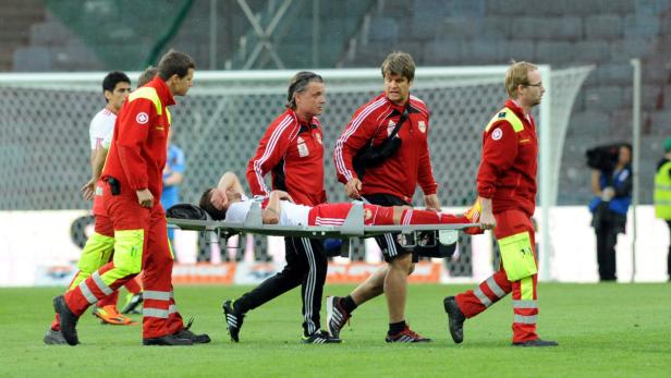 Sanitäter tragen einen verletzten Fußballspieler vom Spielfeld.