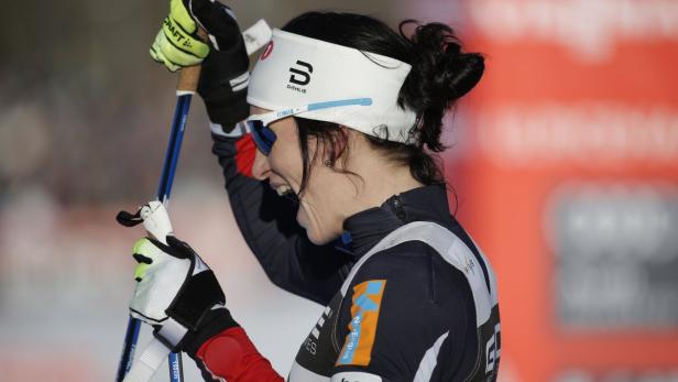 Eine Langläuferin jubelt mit ihren Skistöcken in der Hand.