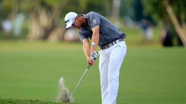 Ein Golfspieler schlägt einen Ball auf einem grünen Golfplatz.