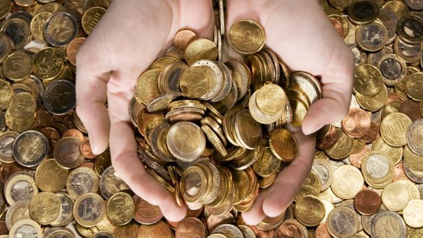 Zwei Hände halten eine große Menge an Euro-Münzen.