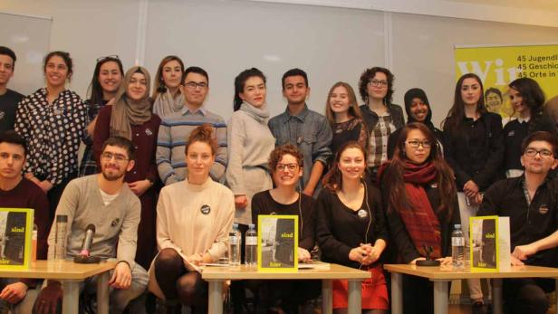 Eine Gruppe junger Menschen posiert für ein Foto vor einem gelben Banner.