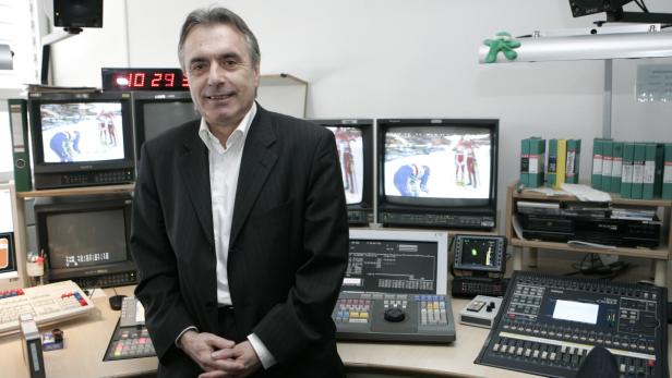 Ein Mann im Anzug steht in einem Fernsehstudio vor Monitoren und Mischpulten.