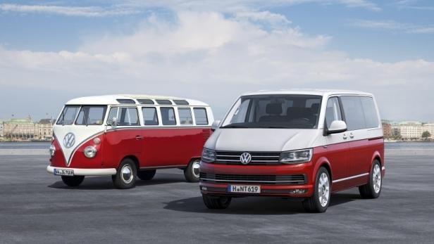 Ein roter und weißer VW-Bus der alten Generation neben einem modernen Modell.