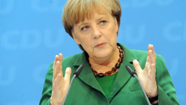 Angela Merkel gestikuliert vor Mikrofonen bei einer Rede.