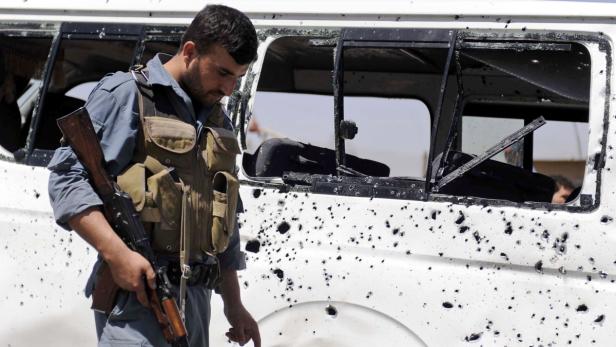 Ein bewaffneter Mann steht vor einem weißen Lieferwagen mit Einschusslöchern.