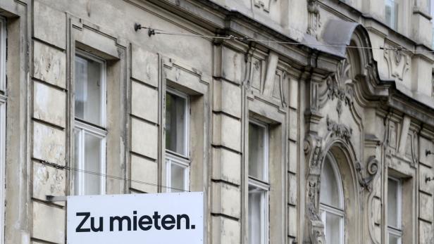 Ein Schild mit der Aufschrift „Zu mieten“ hängt an einer verzierten Fassade.