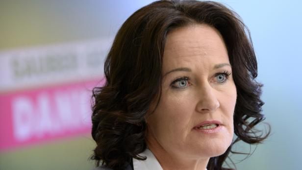 Nahaufnahme einer Frau mit dunklen, gewellten Haaren und hellblauen Augen.