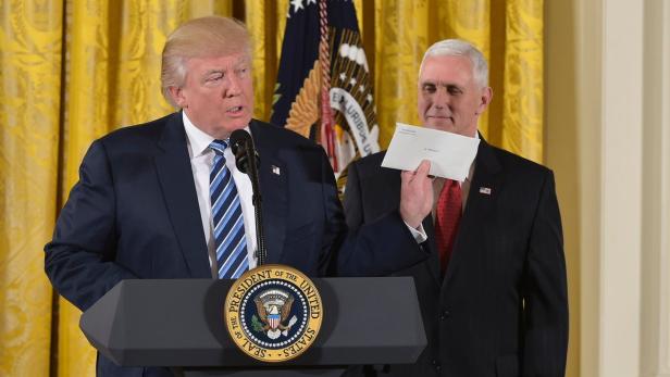Donald Trump hält den Brief von Barack Obama in der Hand.