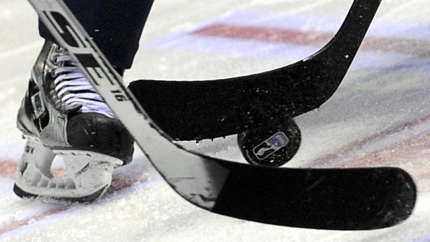 Ein Eishockeyschläger und ein Schlittschuh auf dem Eis mit einem Puck.
